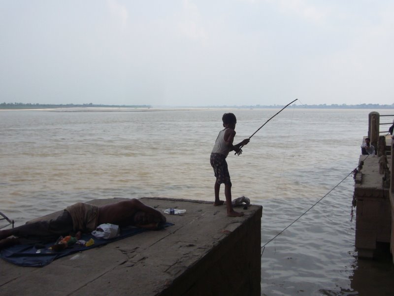 A kid fishes in the brown river ... more likely to be for jewellery than fish.